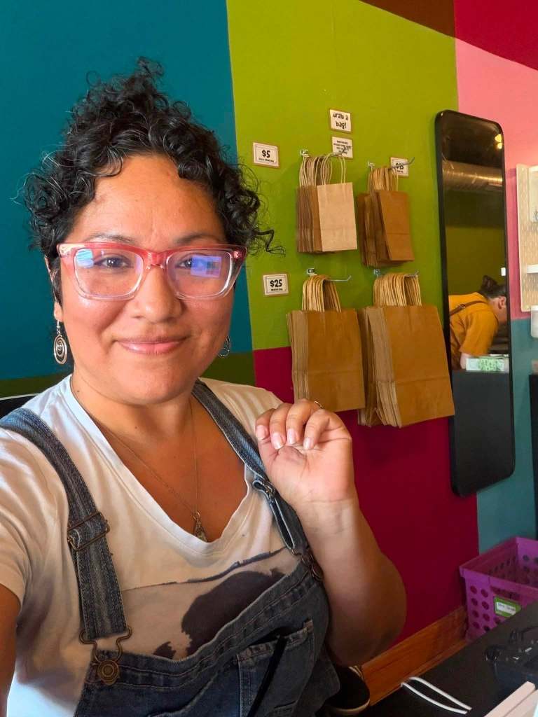 woman with dark hair and glasses taking a smiling selfie