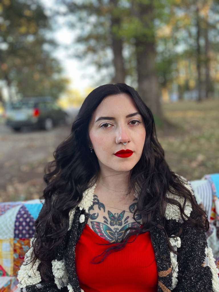 Musician Heather Hammers sitting on a bench looking at the camera.